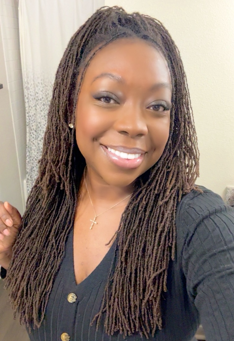 Brittany smiling in a black ribbed cardigan and gold cross necklace